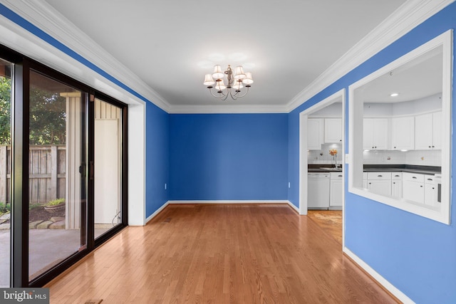 unfurnished dining area featuring crown molding, a sink, light wood-style floors, a chandelier, and baseboards