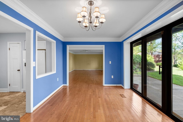 unfurnished dining area with baseboards, light wood finished floors, crown molding, and an inviting chandelier