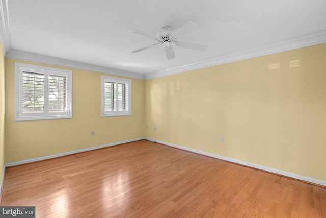 empty room featuring a ceiling fan, baseboards, ornamental molding, and light wood-style flooring