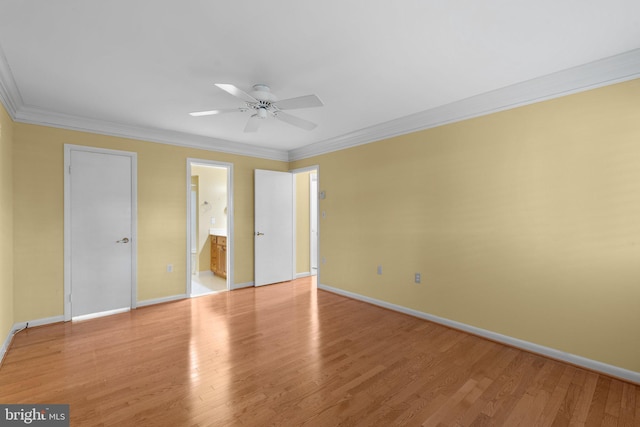 unfurnished bedroom featuring baseboards, crown molding, ensuite bath, and light wood-type flooring