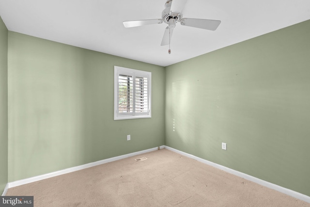 carpeted spare room featuring baseboards, ceiling fan, and visible vents