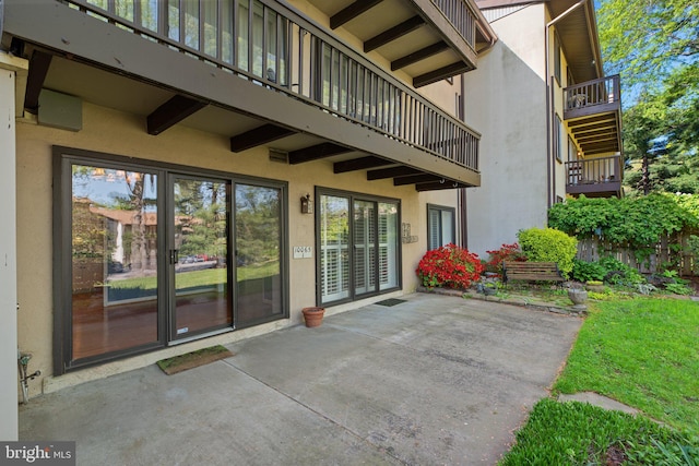 property entrance featuring a patio area, stucco siding, and a balcony