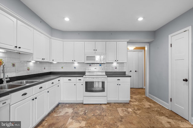 kitchen featuring white appliances, white cabinetry, dark countertops, and a sink