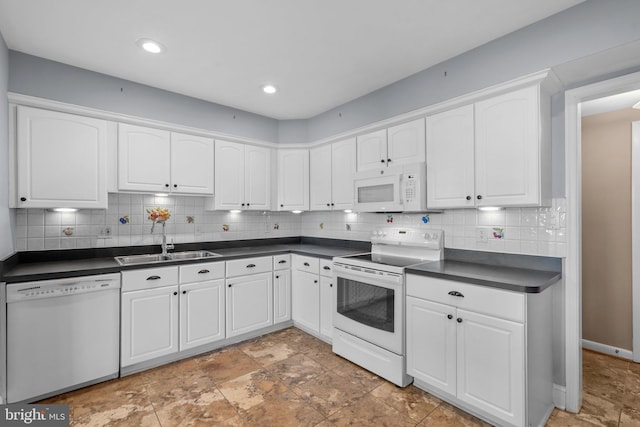 kitchen featuring backsplash, dark countertops, a sink, white cabinets, and white appliances