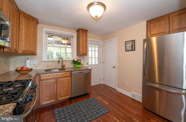 3004 Joshua Rd, Lafayette Hill, PA 19444 - kitchen featuring dark wood-style flooring, a sink, dark stone countertops, stainless steel appliances, and backsplash