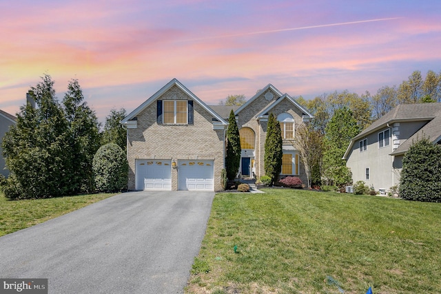 traditional-style house featuring a lawn, driveway, brick siding, and an attached garage