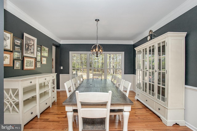 dining area with ornamental molding, light wood finished floors, and an inviting chandelier