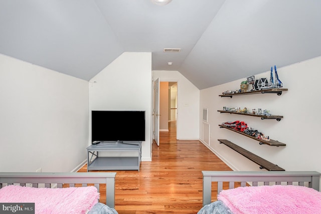 bedroom with light wood finished floors, lofted ceiling, and visible vents