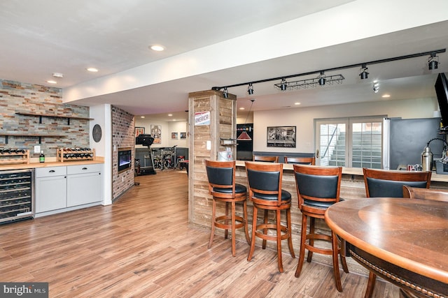 bar featuring wine cooler, light wood-style flooring, rail lighting, and a dry bar