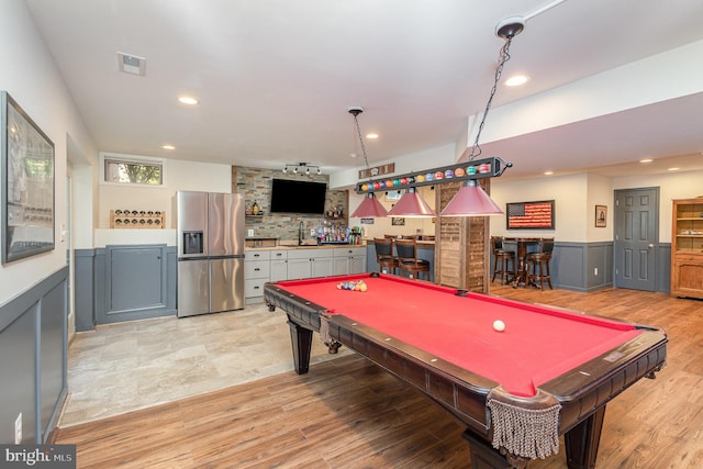 playroom with pool table, light wood finished floors, wainscoting, a sink, and wet bar