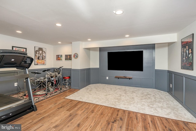 exercise area with a decorative wall, a wainscoted wall, and wood finished floors
