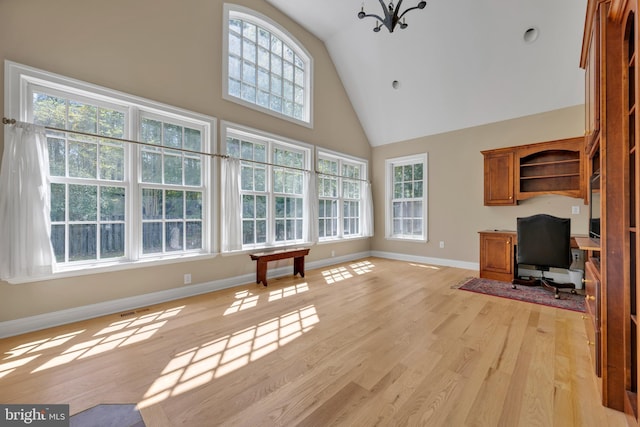 unfurnished living room with high vaulted ceiling, plenty of natural light, baseboards, and light wood-style flooring