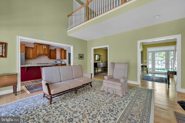 living room with light wood finished floors, baseboards, and a high ceiling