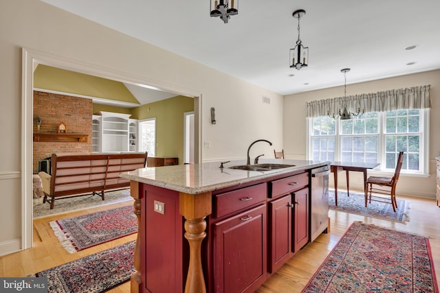 kitchen with a sink, stainless steel dishwasher, reddish brown cabinets, and light wood finished floors