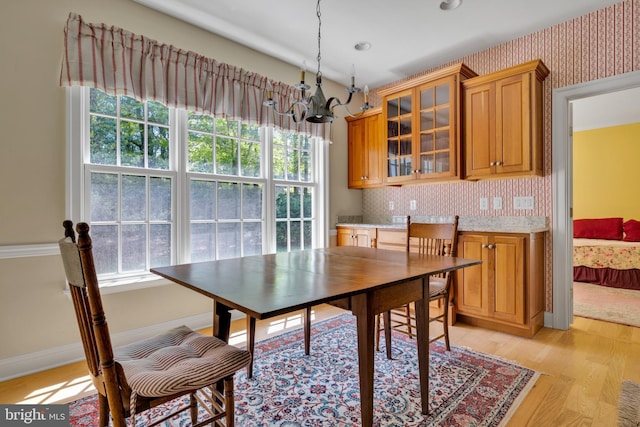 dining space with a chandelier, light wood-type flooring, wallpapered walls, and baseboards