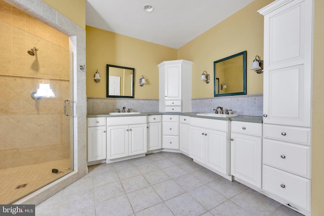 full bath featuring tile walls, tile patterned floors, a shower stall, vanity, and a wainscoted wall