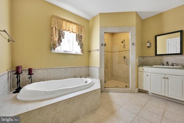 bathroom with a stall shower, a garden tub, tile patterned flooring, vanity, and tile walls