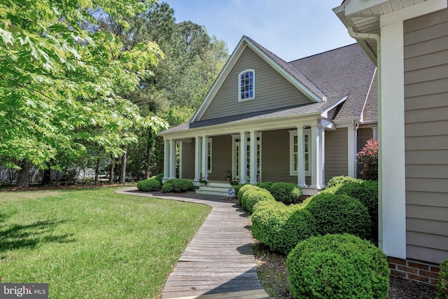 view of front facade featuring a front yard, covered porch, and roof with shingles