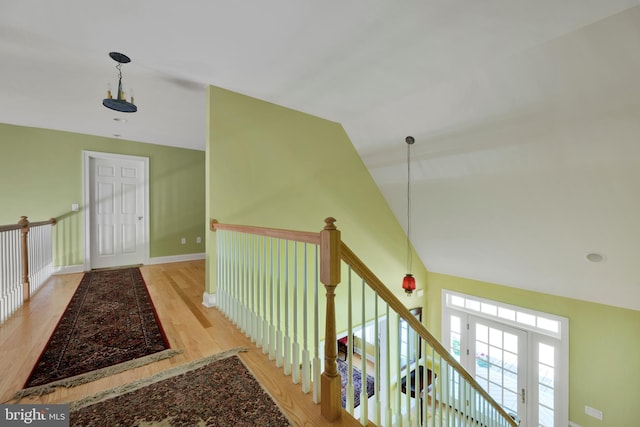 hall with wood finished floors, lofted ceiling, and baseboards