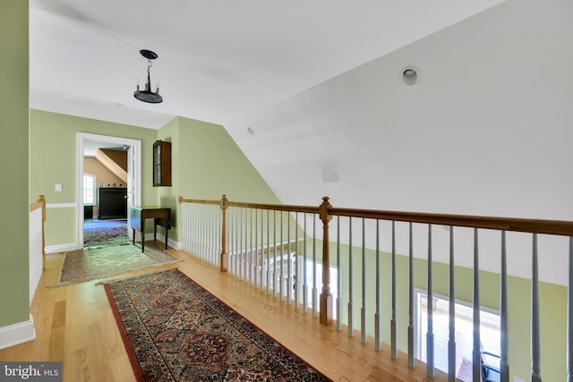 hallway featuring wood finished floors, vaulted ceiling, and baseboards