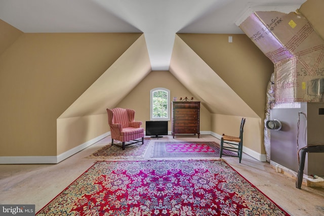 living area featuring vaulted ceiling and baseboards