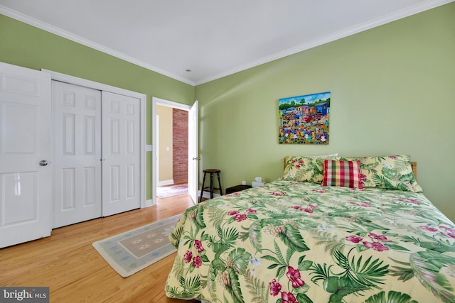 bedroom featuring wood finished floors, crown molding, a closet, and baseboards