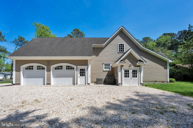 view of front of home featuring an attached garage, central AC, driveway, and a shingled roof