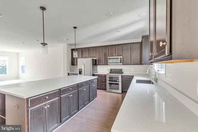 kitchen featuring dark brown cabinetry, a sink, a center island, stainless steel appliances, and wood finished floors
