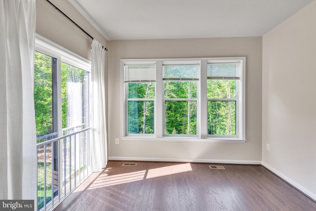 empty room featuring visible vents, baseboards, and wood finished floors