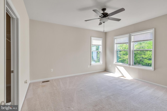 carpeted empty room with baseboards, a ceiling fan, and visible vents