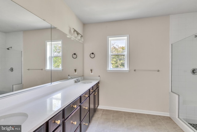 bathroom featuring tile patterned flooring, double vanity, baseboards, a sink, and a tile shower