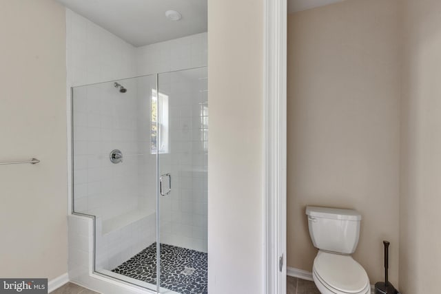 full bath with toilet, baseboards, and a stall shower