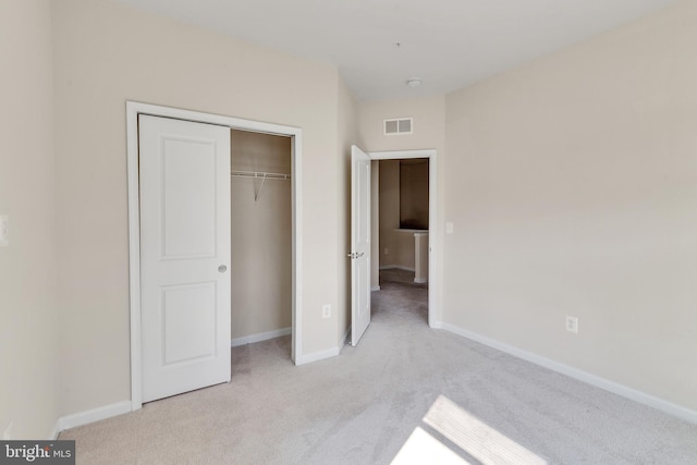 unfurnished bedroom with visible vents, baseboards, a closet, and light colored carpet
