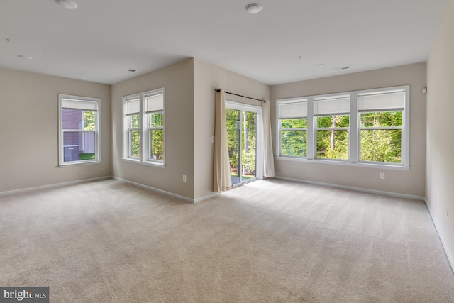 carpeted spare room featuring baseboards and visible vents