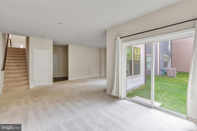 carpeted empty room featuring baseboards and stairway