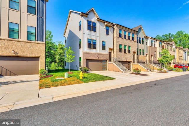 townhome / multi-family property with a garage, brick siding, stairs, board and batten siding, and a residential view