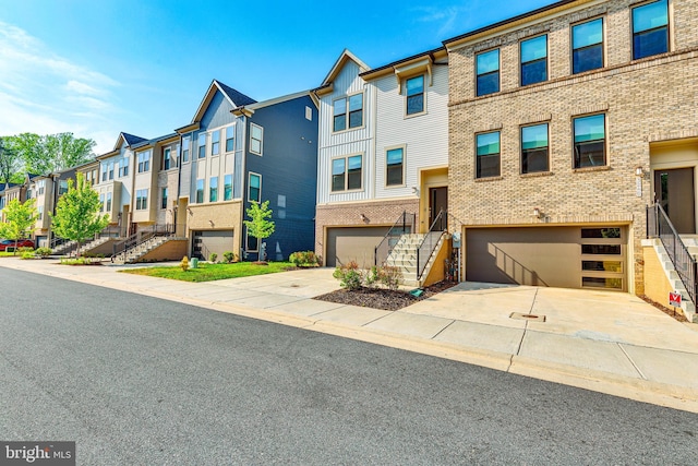 view of property featuring a residential view, stairs, an attached garage, and driveway