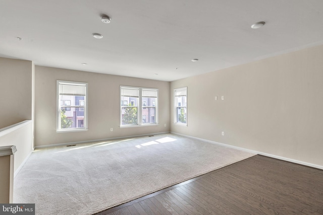 unfurnished room featuring carpet floors, baseboards, and wood finished floors