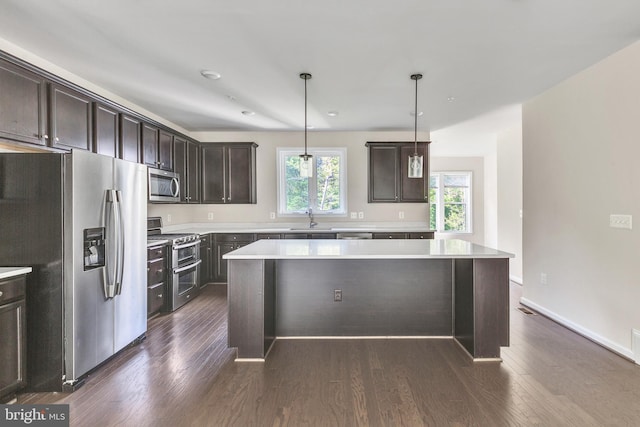 kitchen featuring dark brown cabinetry, a kitchen island, a sink, light countertops, and stainless steel appliances