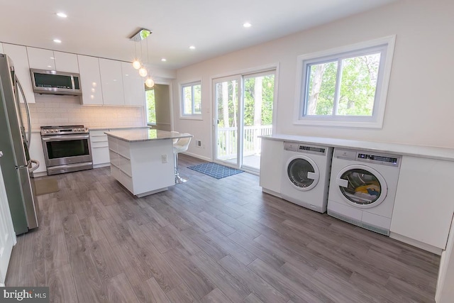 interior space featuring appliances with stainless steel finishes, separate washer and dryer, white cabinetry, backsplash, and modern cabinets