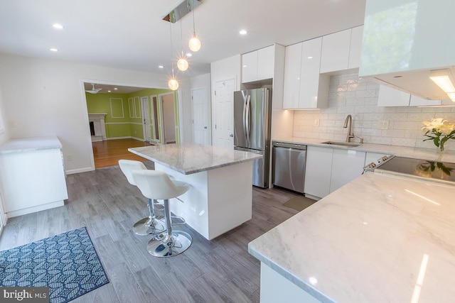 kitchen featuring a kitchen island, modern cabinets, white cabinets, a sink, and stainless steel appliances
