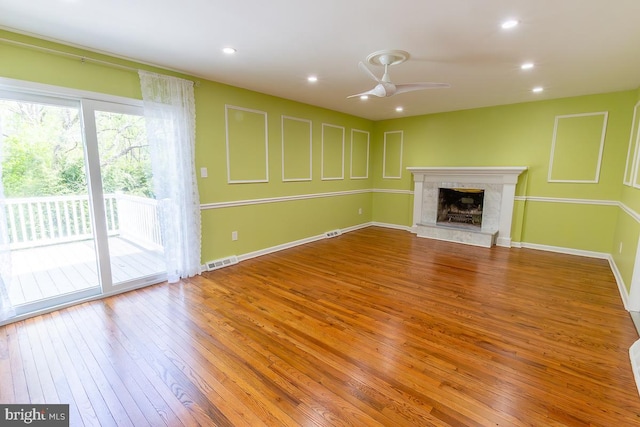unfurnished living room featuring a fireplace, hardwood / wood-style floors, a ceiling fan, baseboards, and visible vents
