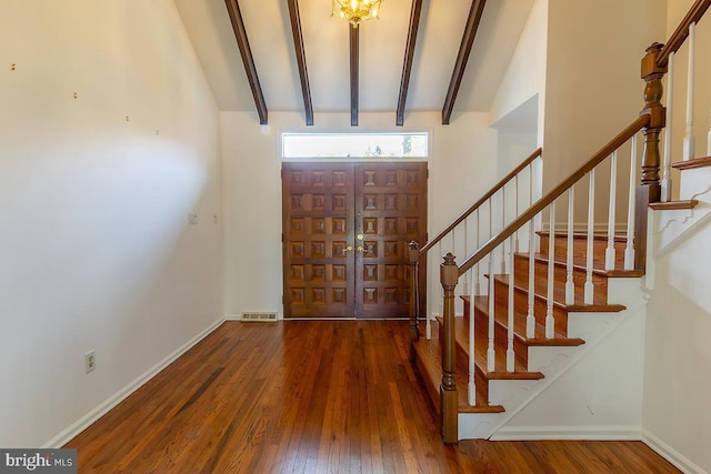 foyer with visible vents, beam ceiling, wood finished floors, and stairway