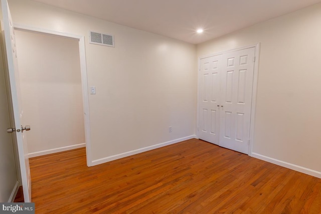 unfurnished bedroom featuring visible vents, a closet, wood finished floors, baseboards, and recessed lighting