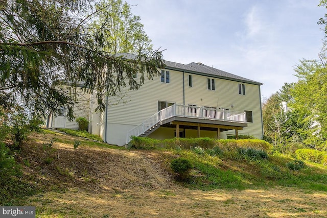 rear view of property featuring stairway and a deck