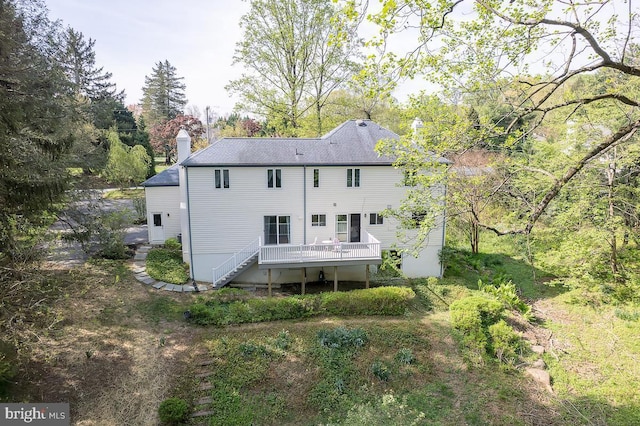 rear view of house featuring a wooden deck, stairs, and a chimney