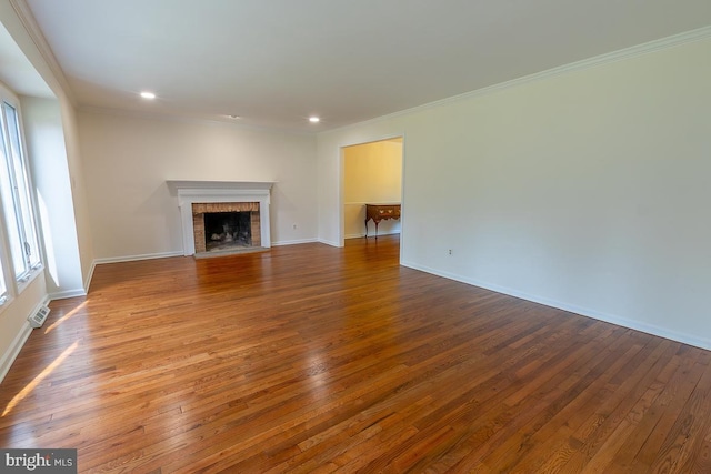unfurnished living room featuring crown molding, a brick fireplace, and hardwood / wood-style floors