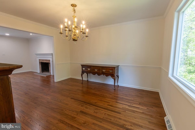 dining room with a notable chandelier, a brick fireplace, wood finished floors, visible vents, and ornamental molding