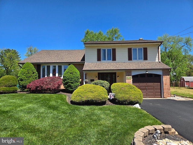 split level home featuring a garage, a front yard, driveway, roof with shingles, and brick siding