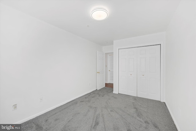unfurnished bedroom featuring baseboards, carpet, and a closet